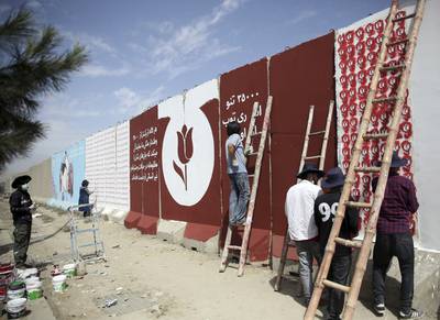 In this Friday, Aug. 30, 2019 photo, independent Afghan artists paints tulips on blast walls in Kabul, Afghanistan.