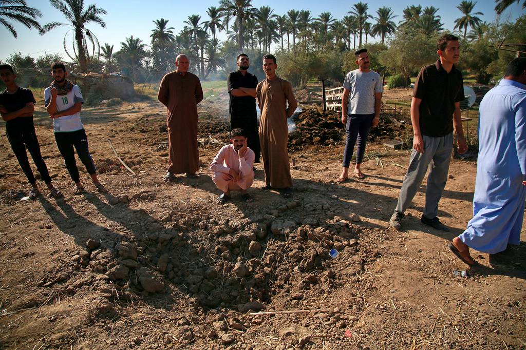 People inspect a crater caused by a deadly Katyusha rocket attack near international airport in Baghdad, Iraq, Tuesday, Sept. 29, 2020.