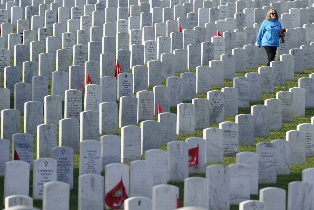 A visitor walks among headstones in Section 60 at Arlington National Cemetery, Nov. 11, 2021, in Arlington, Va. Section 60 is where the men and women who died in America's most recent wars, especially Iraq and Afghanistan, are buried.