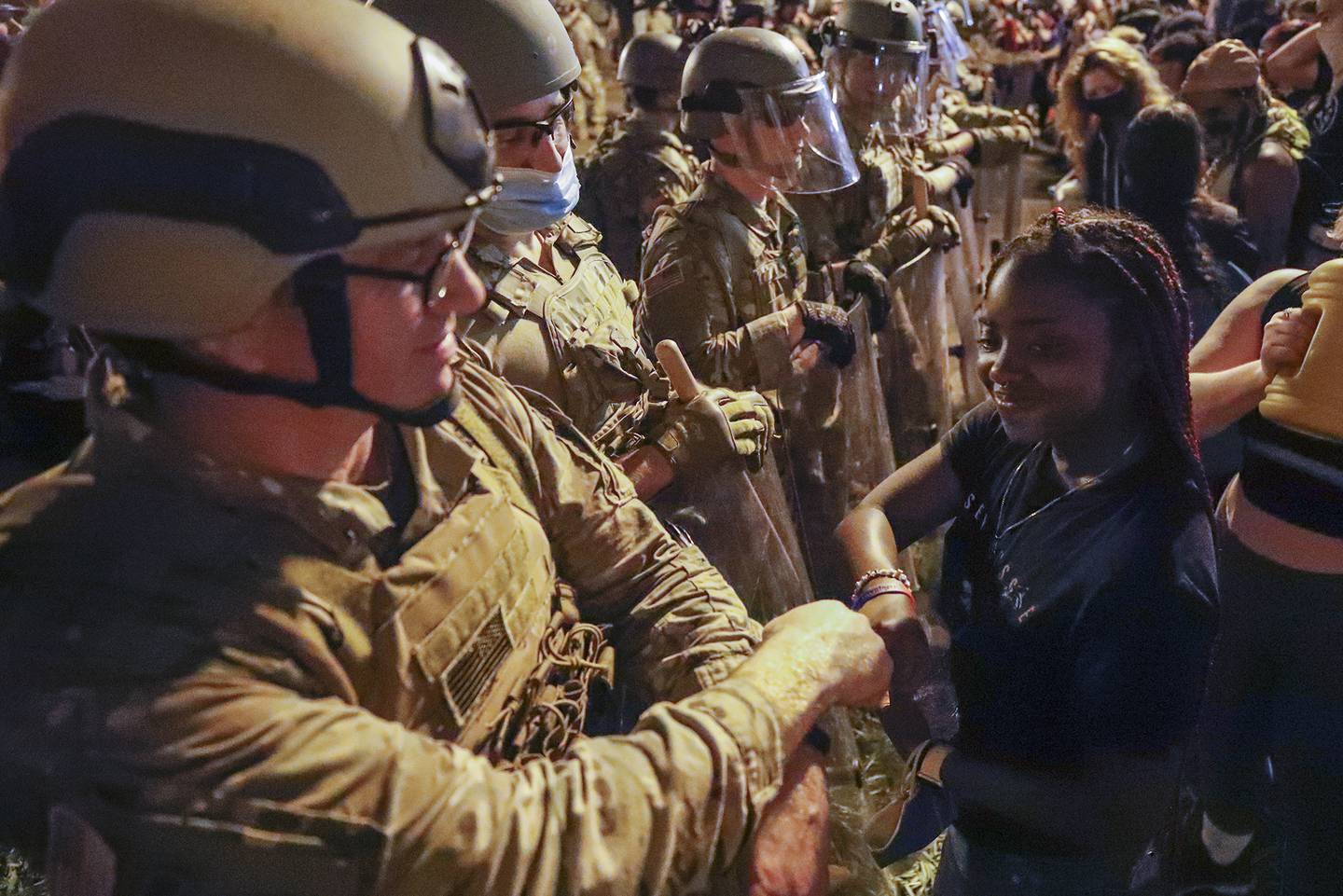 A Utah National Guard solider fist-bumps with a demonstrator as protests over the death of George Floyd continue, Wednesday, June 3, 2020, near the White House in Washington.