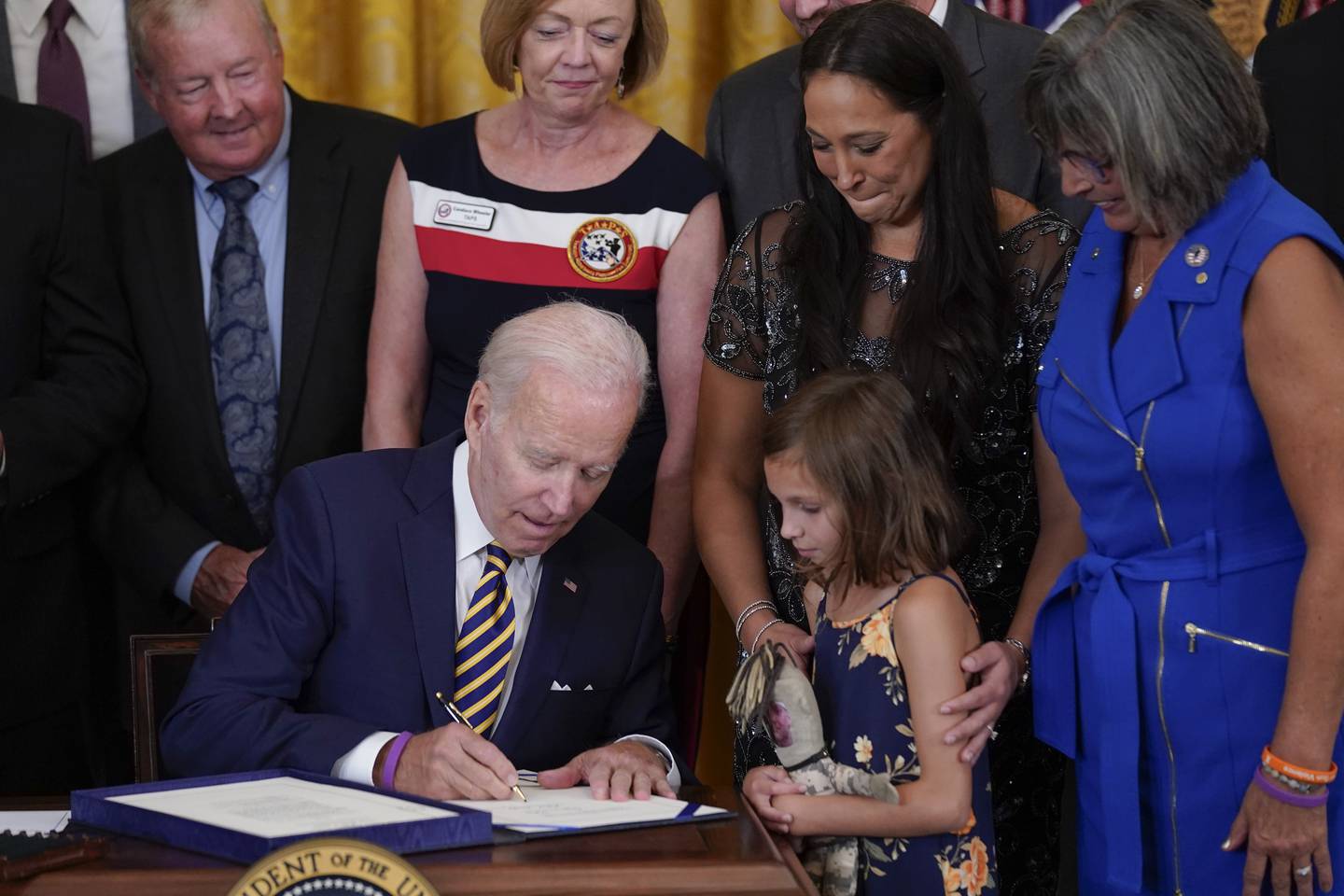 Danielle and Brielle Robinson, the wife and daughter of Sgt. 1st Class Heath Robinson, who died of cancer two years ago watch as President Joe Biden signs the "PACT Act of 2022" during a ceremony in the East Room of the White House, Wednesday, Aug. 10, 2022, in Washington.