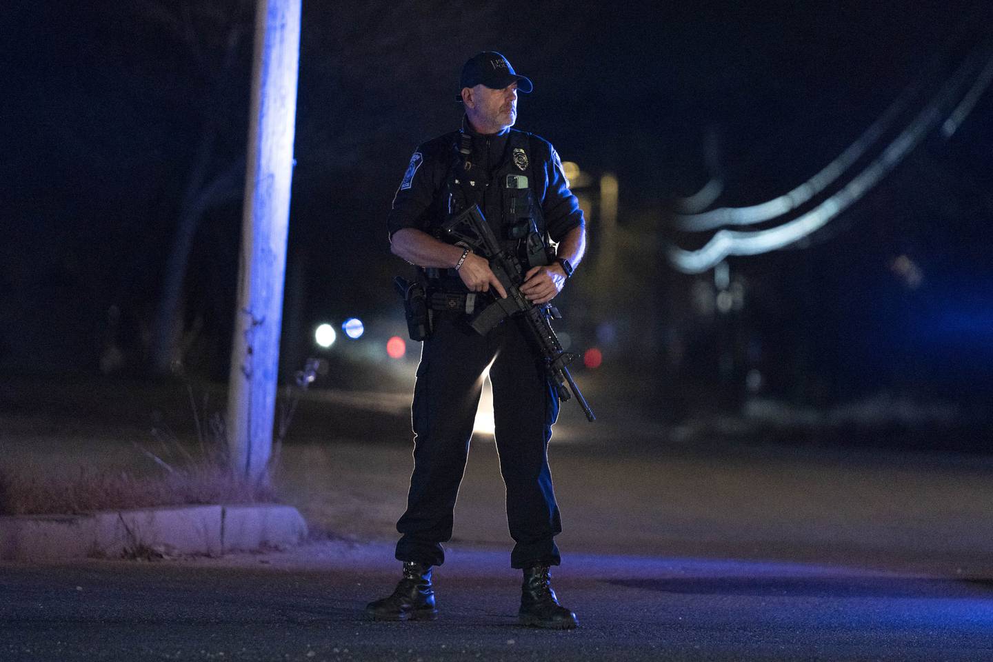 A police officer guards the road to a recycling facility where the body of Robert Card, the suspect in this week's mass shootings, was found, Friday, Oct. 27, 2023, in Lisbon, Maine.