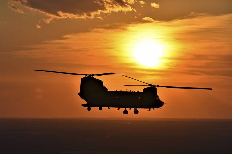 The sunset is visible behind a CH-47 Chinook helicopter as it flies near Fort Hood, Texas.