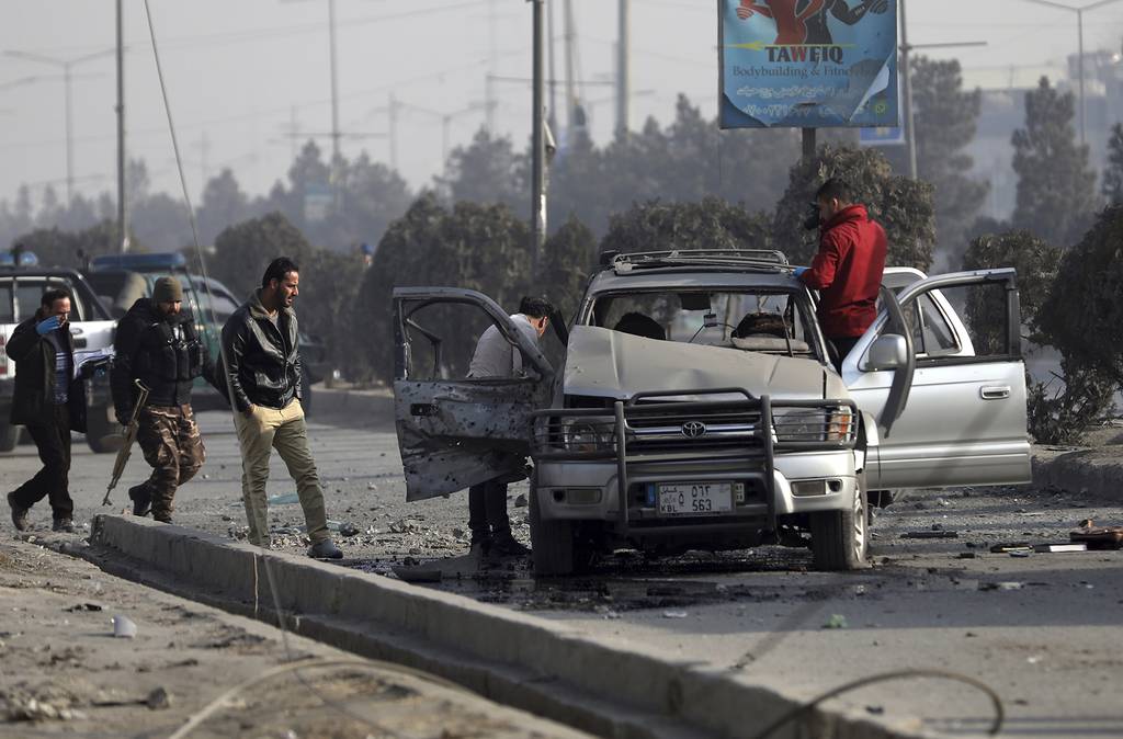 Security personnel inspect the site of a bomb attack in Kabul, Afghanistan, Tuesday, Feb. 2, 2021.