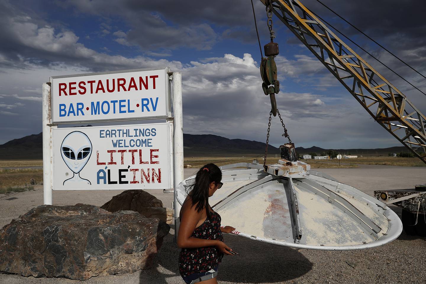 In this July 22, 2019, photo, Grace Capati looks at a UFO display outside of the Little A'Le'Inn, in Rachel, Nev., the closest town to Area 51.