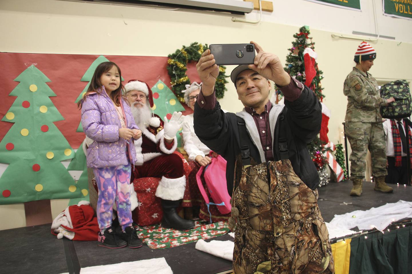 A parent takes a selfie with a child and Santa and Mrs. Claus in Nuiqsut, Alaska, on Nov. 29, 2022.
