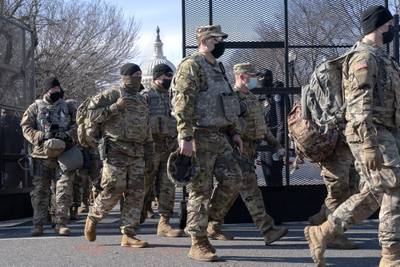 With the U.S. Capitol in the background, members of the National Guard change shifts as they exit through anti-scaling security fencing on Saturday, Jan. 16, 2021, in Washington as security is increased ahead of the inauguration of President-elect Joe Biden and Vice President-elect Kamala Harris.