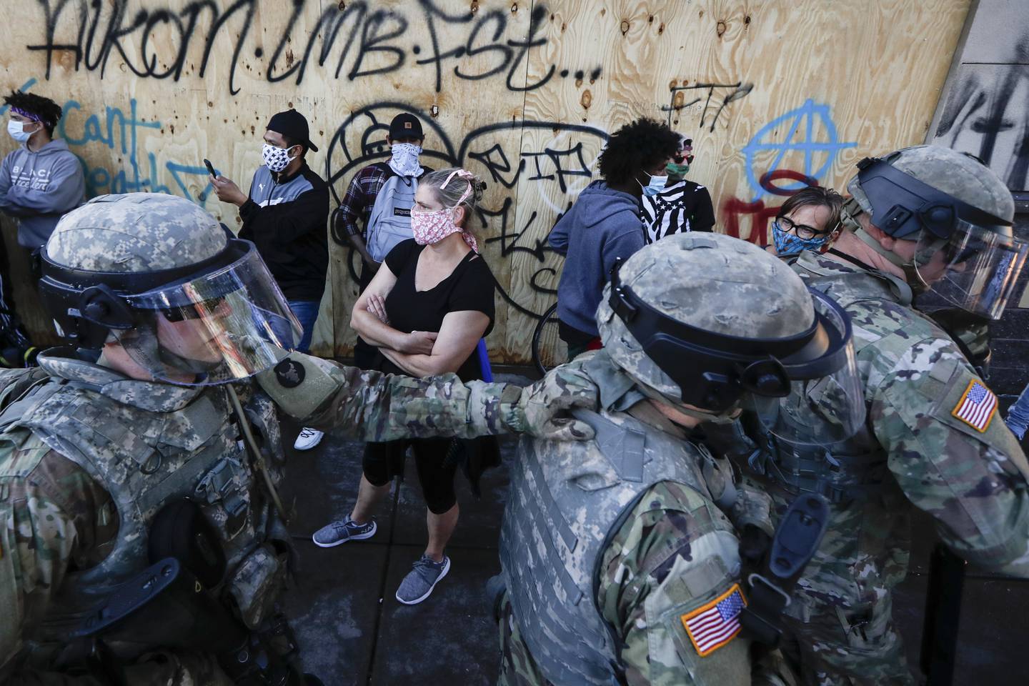 National Guard personnel return to their defensive position as protesters make room for them to fall back following a confrontation on East Lake Street, Friday, May 29, 2020, in St. Paul, Minn.