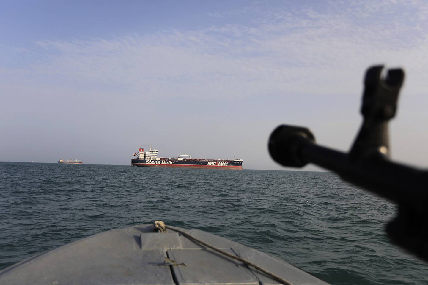In this July 21, 2019 photo, a speedboat of Iran's Revolutionary Guard trains a weapon toward the British-flagged oil tanker Stena Impero, which was seized in the Strait of Hormuz on Friday by the Guard, in the Iranian port of Bandar Abbas.