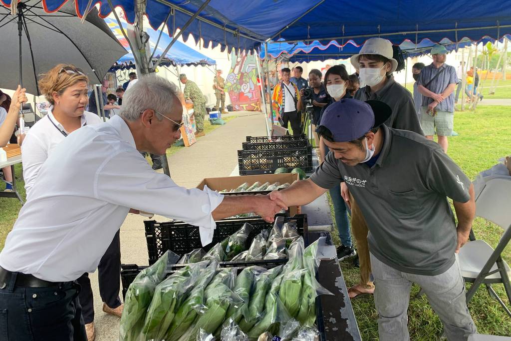 U.S. Ambassador to Japan Rahm Emanuel shakes hands with a local vendor at the farmers market at Camp Hansen, a U.S. Marine Corps base on a southern Japanese island of Okinawa, Sunday, Oct. 30, 2022.