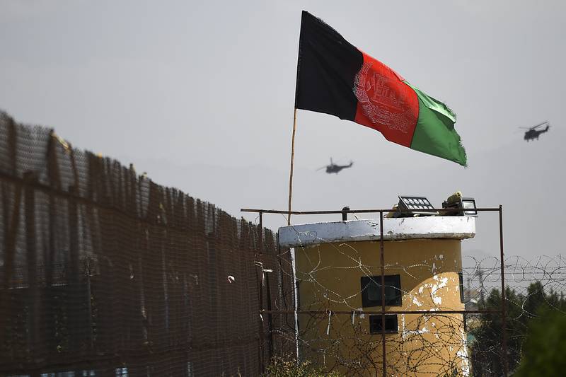 Two U.S. military helicopters are seen flying past an Afghan national flag during the 100th anniversary of the country's Independence Day in Kabul on Aug. 19, 2019.