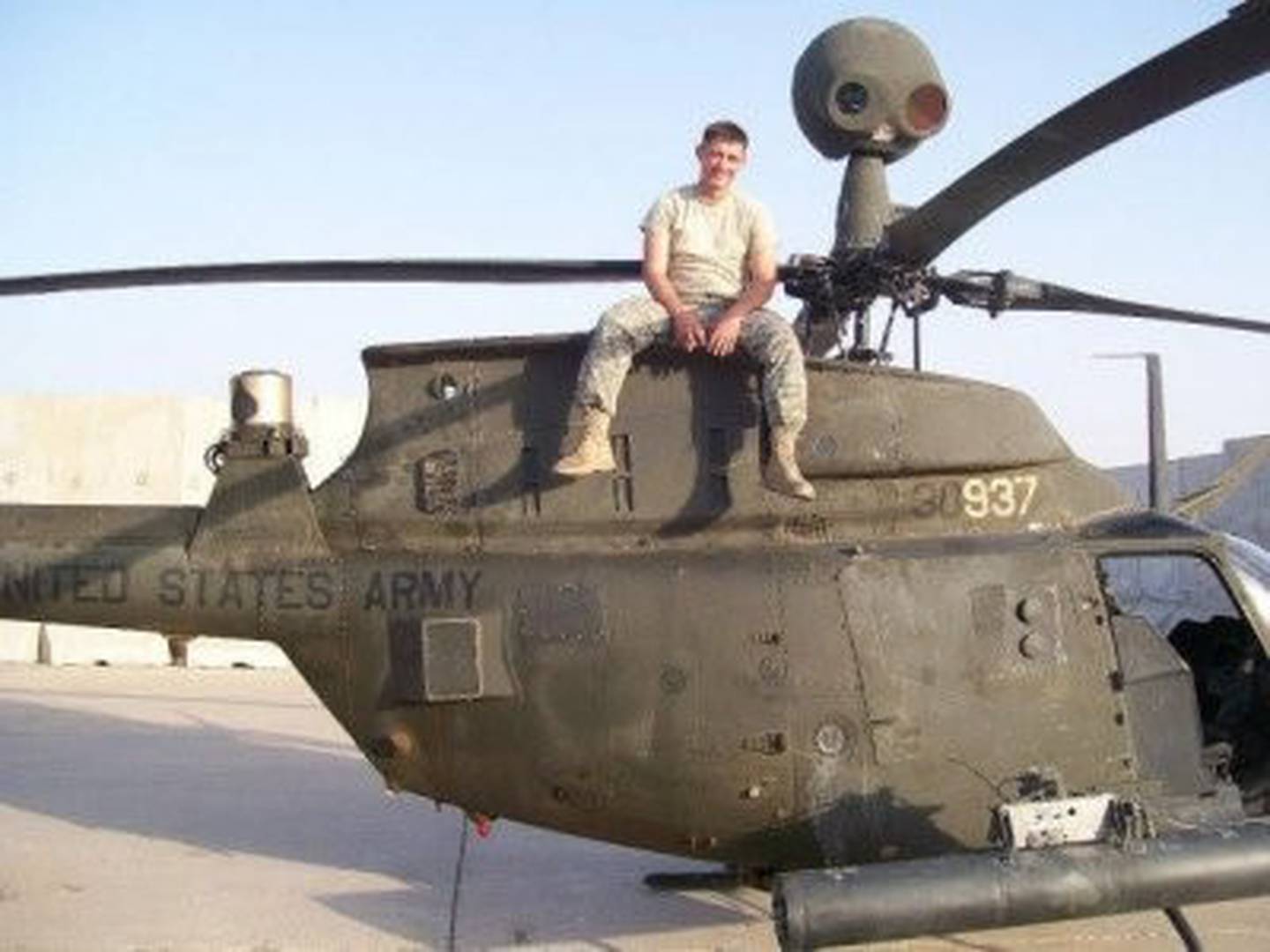 B.B. Sanders sits atop an OH-58D in the desert sun while doing line maintenance during the Iraqi surge.