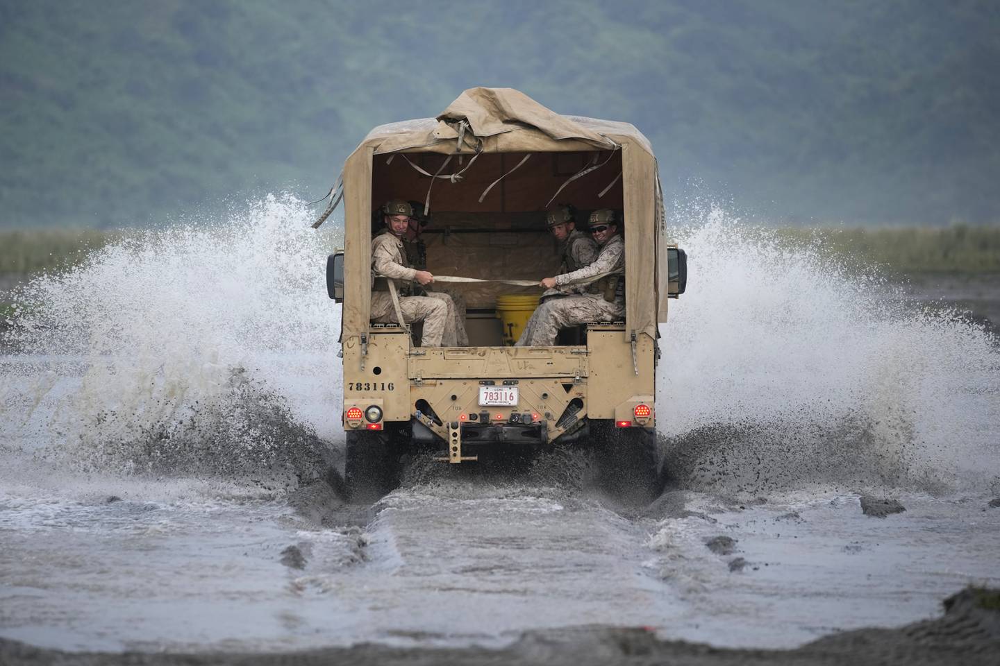 American Marines ride their vehicle across a stream during annual combat drills between the Philippine Marine Corps and U.S. Marine Corps in Capas, Tarlac province, northern Philippines, Thursday, Oct. 13, 2022.