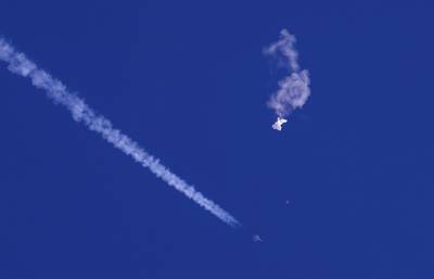 A fighter jet flies past the remnants of a large balloon after it was shot down above the Atlantic Ocean, just off the coast of South Carolina near Myrtle Beach, Feb. 4, 2023.