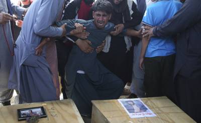 A relative wails near the coffins of victims of the Dubai City wedding hall bombing during a mass funeral in Kabul, Afghanistan, Sunday, Aug.18, 2019.
