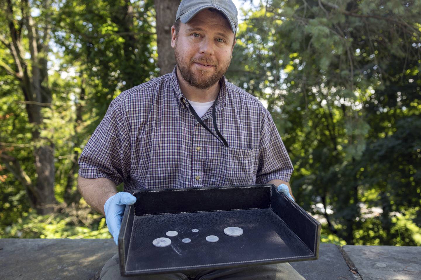This photo, provided by the U.S. Military Academy at West Point, Aug. 30, 2023, shows West Point archeologist Paul Hudson displaying coins found in the lead box believed to have been placed in the base of a monument by cadets almost two centuries ago, in West Point, NY.