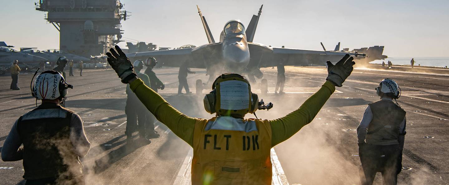 A sailor directs an F/A-18E Super Hornet on the flight deck of the aircraft carrier USS Nimitz (CVN 68) during flight operations on Jan. 17, 2021, in the Arabian Sea.