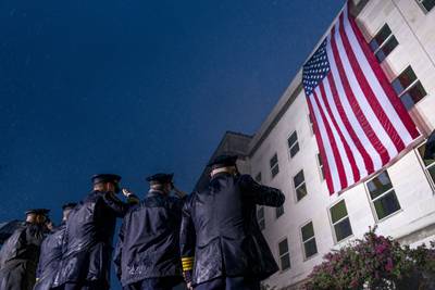 First responders salute in a driving rain as a U.S. flag is unfurled at the Pentagon in Washington, Sunday, Sept. 11, 2022, at sunrise on the morning of the 21st anniversary of the 9/11 terrorist attacks.