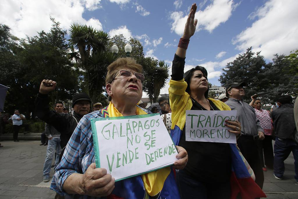 A woman holds a sign with a message that reads in Spanish; “Galapagos is not to be sold, but to be defended,” during a protest against the government’s plan to allow the U.S. military to use a Galapagos island for aircraft on anti-drug trafficking flights, outside the government palace in Quito, Ecuador,