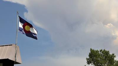 A Colorado flag flies over the West Fork Complex Fire as seen from Pagosa Springs Colo., June 27, 2013.