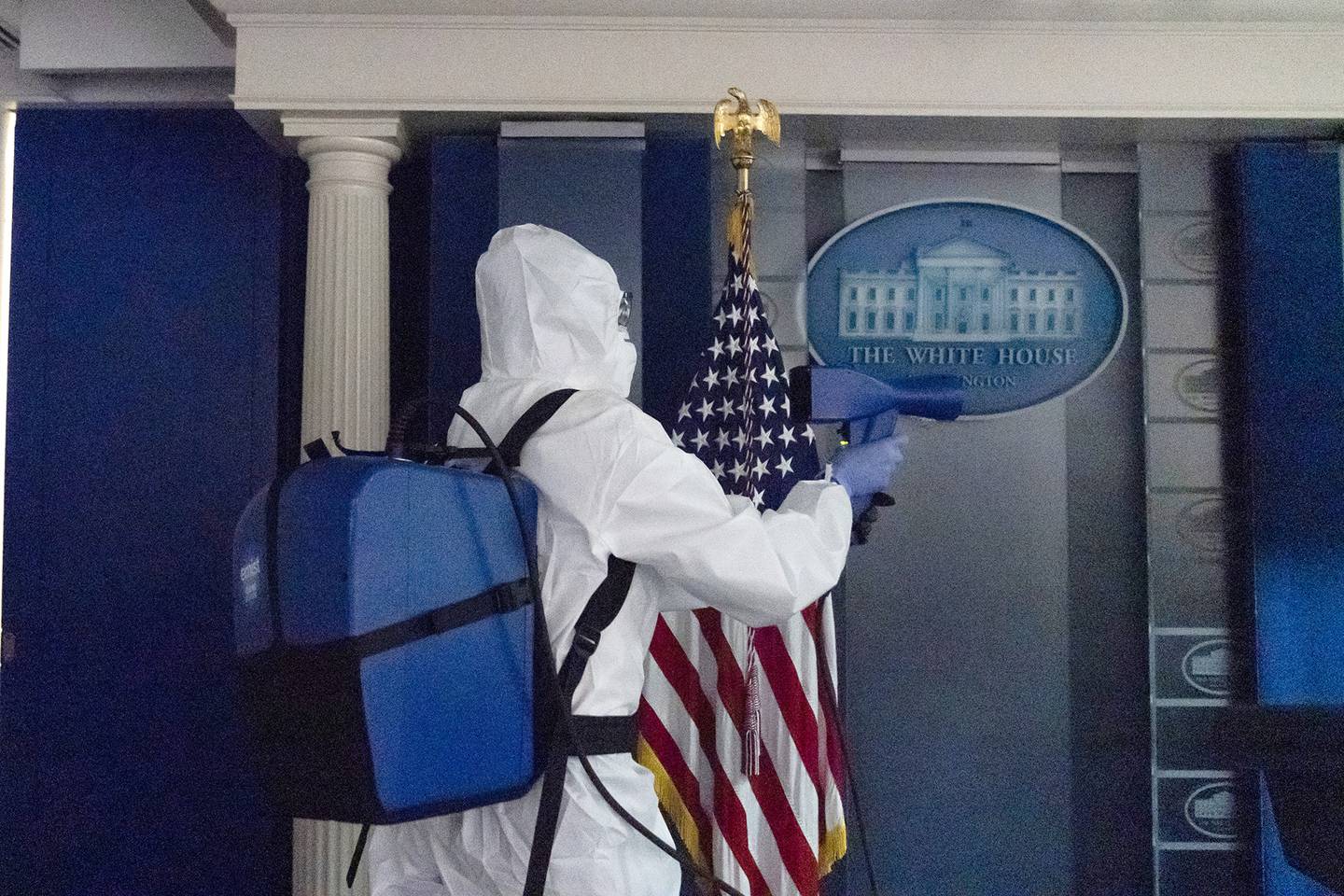 A member of the cleaning staff sprays The James Brady Briefing Room of the White House, Monday, Oct. 5, 2020, in Washington.