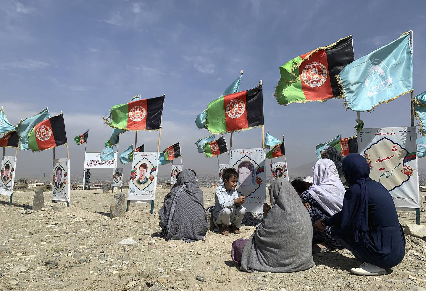 In this Sept 14, 2020, file photo, families gather at the graves of their relatives, adorned with their pictures, on the outskirts of Kabul, Afghanistan.