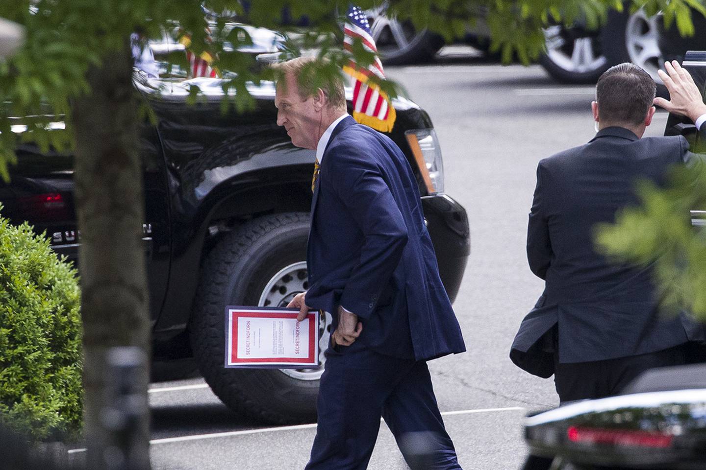 Outgoing acting Defense Secretary Patrick Shanahan arrives for a meeting with President Donald Trump about Iran carrying a folder marked secret