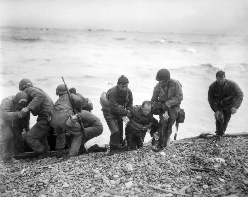 members of an American landing unit help their comrades ashore during the Normandy invasion
