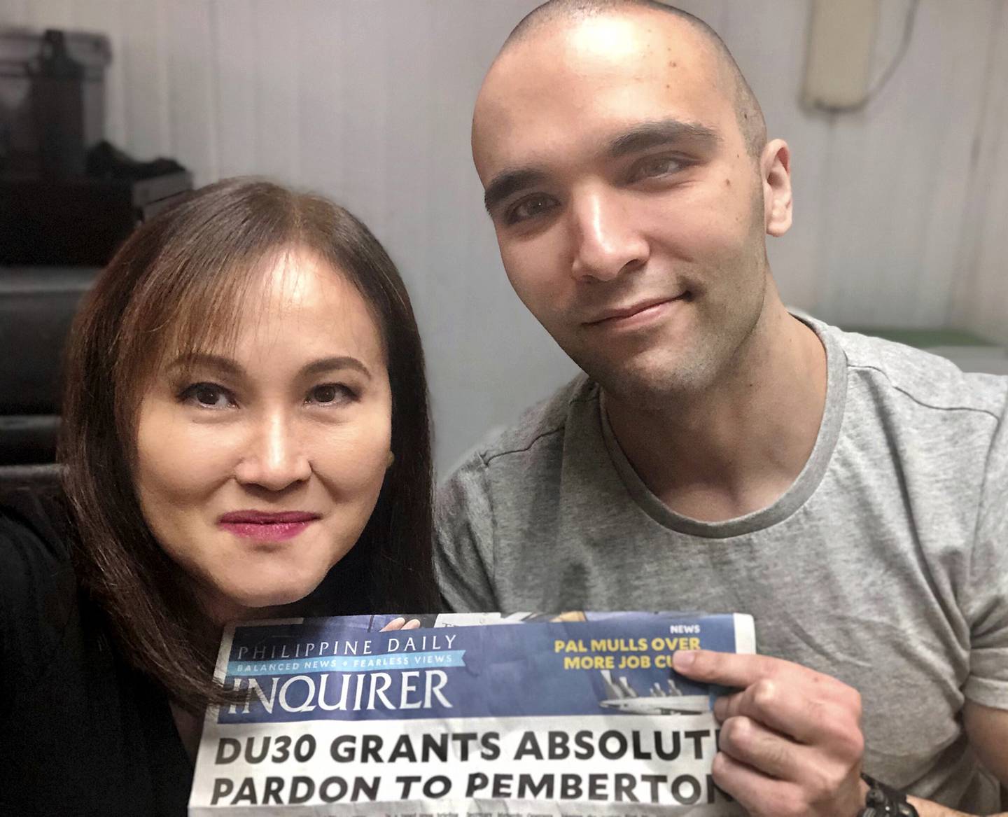 U.S. Marine Lance Cpl. Joseph Scott Pemberton, right, poses for a selfie while showing the headlines of a newspaper beside his lawyer Rowena Garcia-Flores on Tuesday Sept. 8, 2020, in Camp Aguinaldo, Quezon city, Philippines