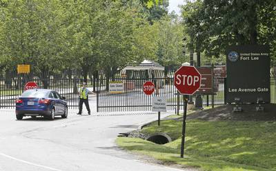 This Aug. 25, 2014, file photo shows security guards opening a gate for motorist at the visitor entrance to Fort Lee, Va.