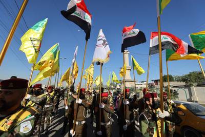 Fighters lift flags of Iraq and paramilitary groups, including al-Nujaba and Kataib Hezbollah, during a funeral in Baghdad, Iraq, following a U.S. strike.