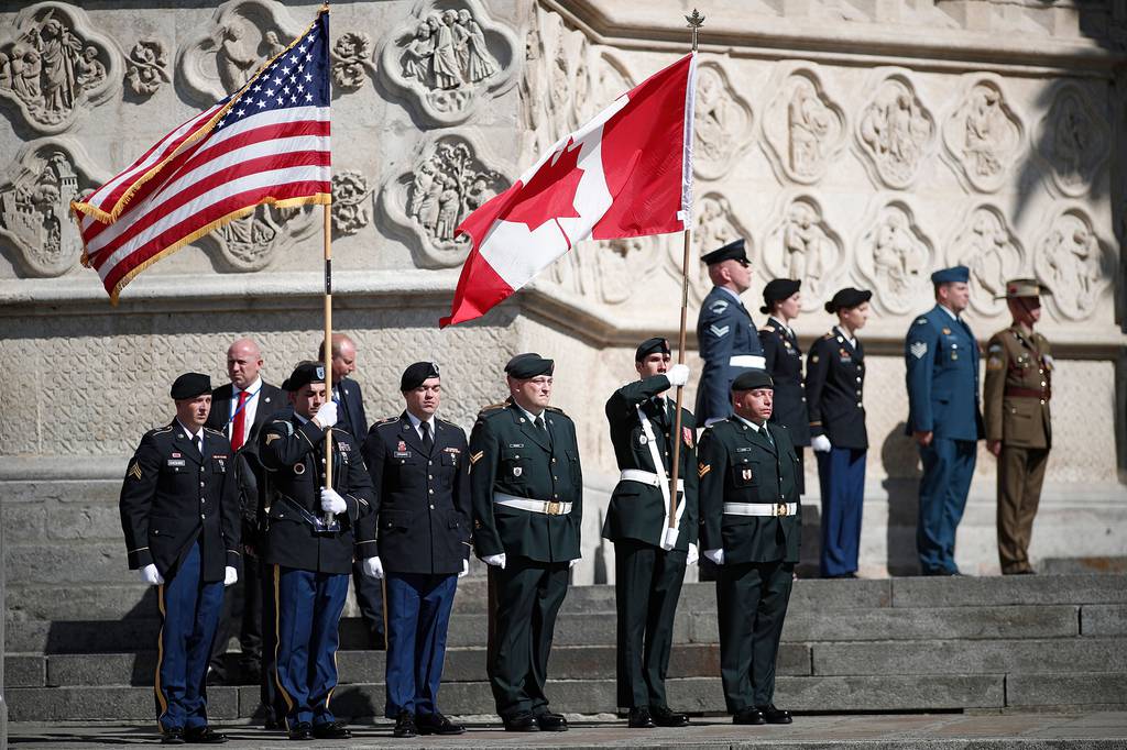 U.S. and Canadian flag bearers stand at attention outside the cathedral after a religious ceremony to mark the 100th anniversary of the World War I Battle of Amiens, at the Cathedral in Amiens, France, Aug. 8, 2018.