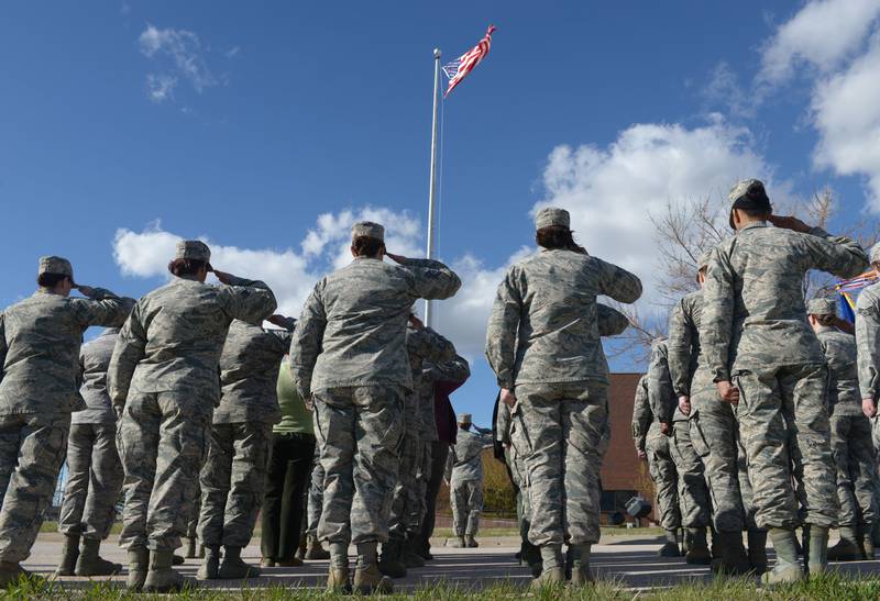Airmen salute the American flag as it is lowered during the women's retirement ceremony at Ellsworth Air Force Base, SD, April 7, 2016.