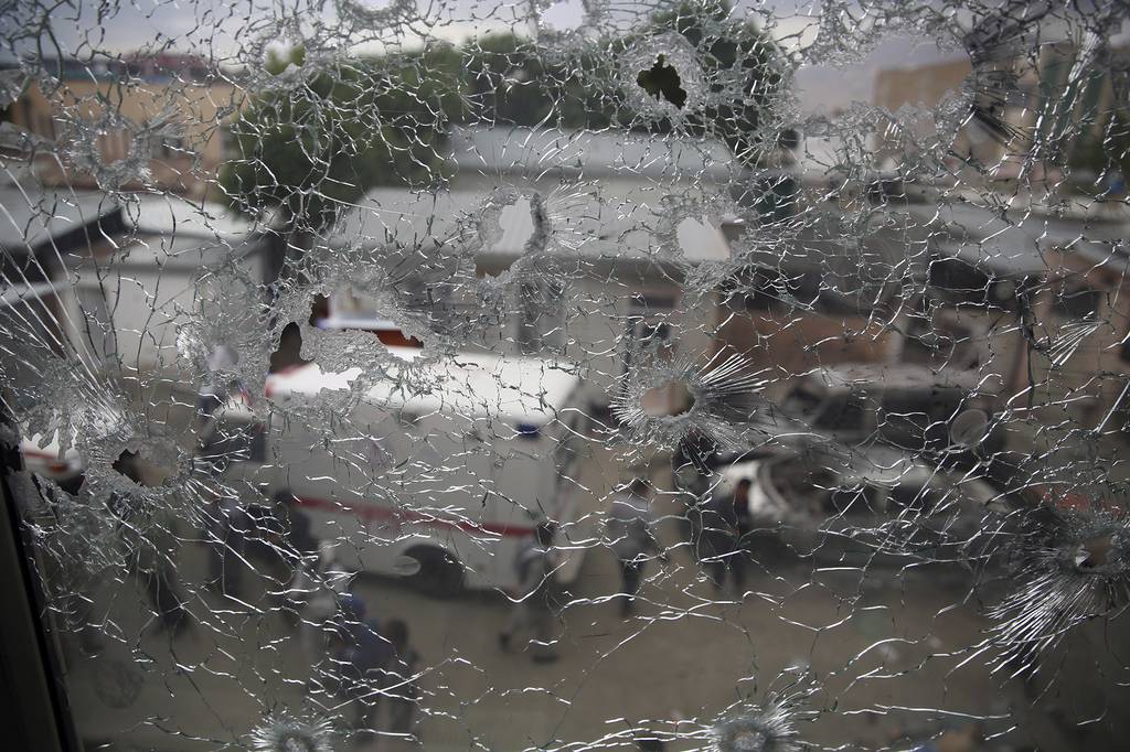 Afghan security security officers are seen through the shattered window of a maternity hospital after gunmen attacked, in Kabul, Afghanistan, Tuesday, May 12, 2020.