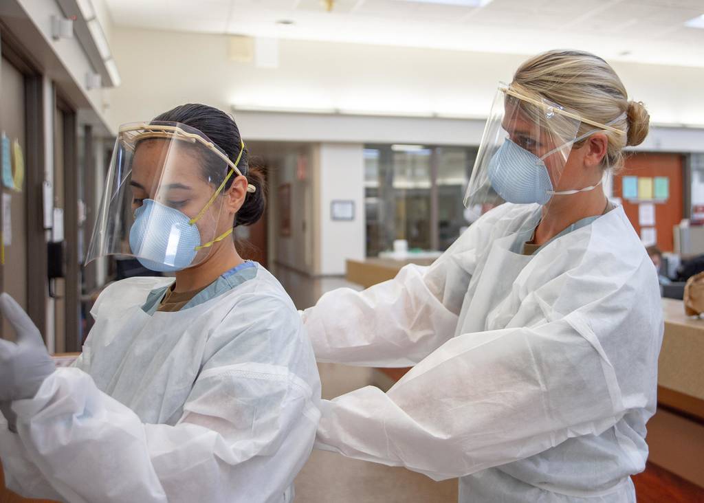 Ensign Kaitlyn Leibing, right, helps Hospitalman Angela Mello don personal protective equipment (PPE) before entering a COVID-19-positive, non-critical patient’s room at Naval Medical Center San Diego on Aug. 4, 2020.