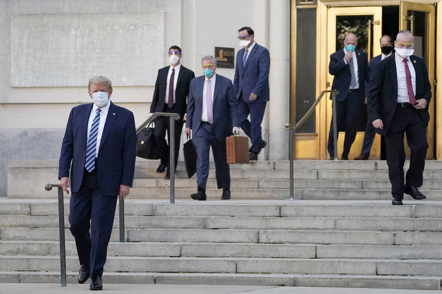 President Donald Trump, left, walks out of Walter Reed National Military Medical Center to return to the White House after receiving treatments for COVID-19, Monday, Oct. 5, 2020, in Bethesda, Md.