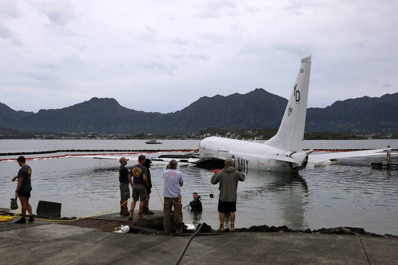 Contractors place inflatable bags under a U.S. Navy P-8A in Kaneohe Bay, Hawaii, Friday, Dec. 1, 2023, so they can float the aircraft over the water and onto land.