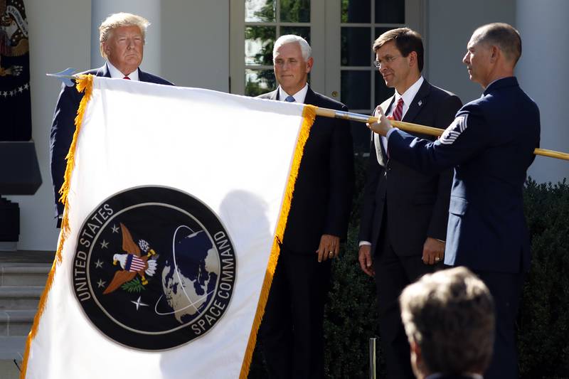 In this Aug. 29, 2019, file photo, President Donald Trump watches with Vice President Mike Pence and then-Defense Secretary Mark Esper as the flag for U.S. Space Command is unfurled as Trump announces the establishment of the U.S. Space Command in the Rose Garden of the White House in Washington.