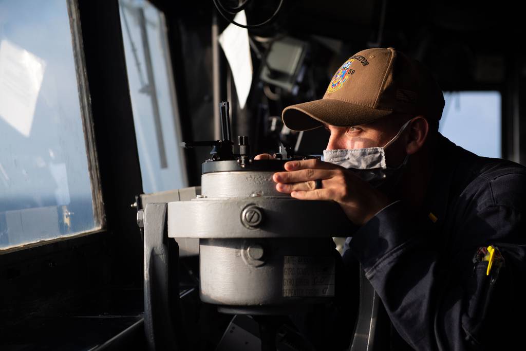 Ensign Chris Luna takes a navigational bearing while standing watch in the pilot house of the guided-missile cruiser USS Princeton (CG 59) on Dec. 21, 2020, in the Indian Ocean.
