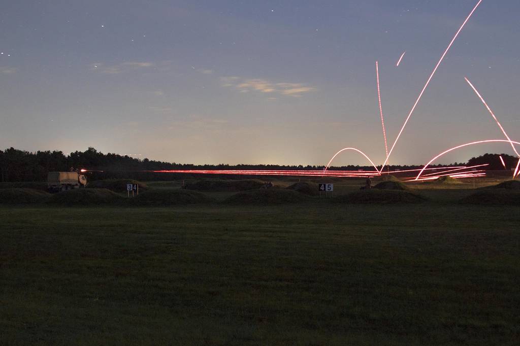 Soldiers from the 1058th Transportation Company, Massachusetts National Guard, conduct a night base defense live-fire exercise under the illumination of a green flare during the Combined Arms Exercise: Patriot Crucible at Joint Base Cape Cod on Aug. 1, 2019.