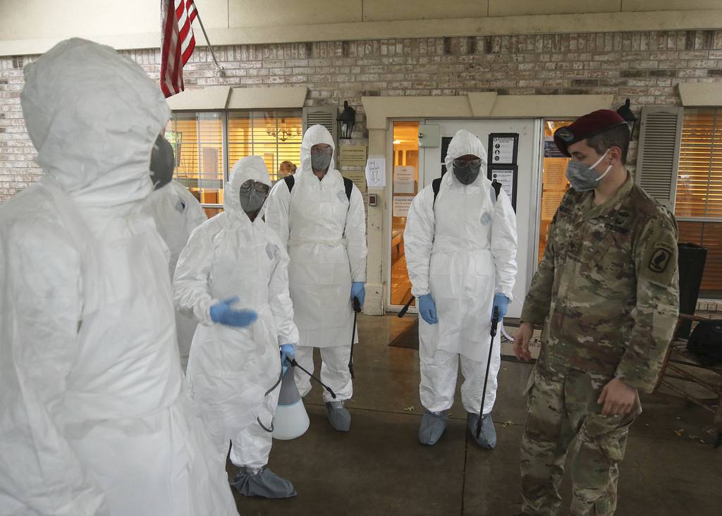 Army National Guard Spc. Joel Mendoza, a chemical, biological, radiological, and nuclear specialist with the 1st Battalion (Airborne) of the 143rd Infantry Regiment, advises members of Joint Task Force 176 on proper wear of personal protective equipment in preparation for disinfecting the West Oaks Nursing and Rehabilitation Center in Austin, Texas, May 12, 2020.