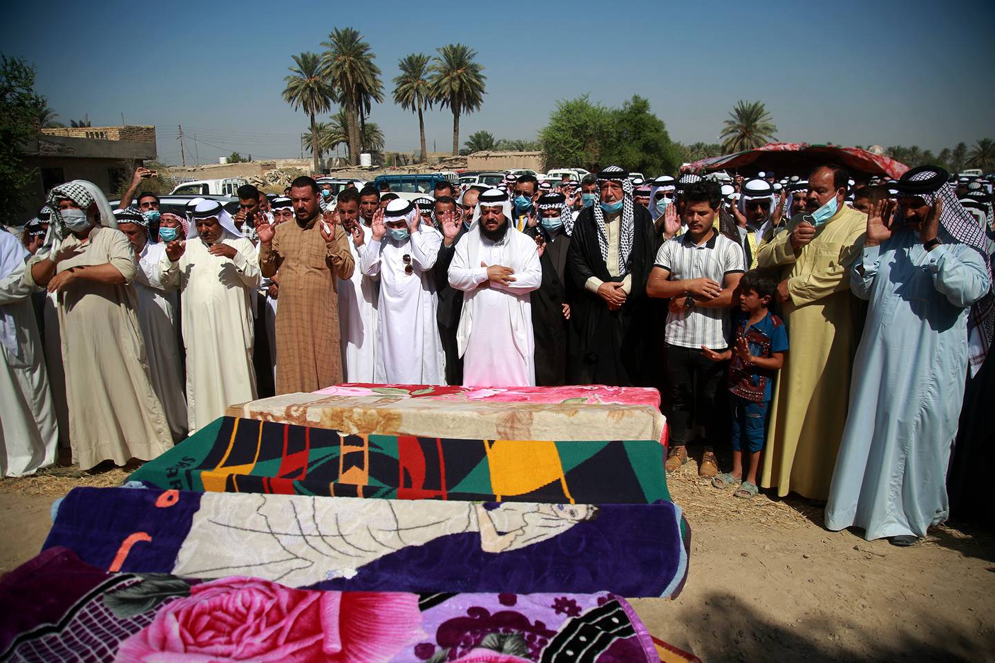 Mourners pray over the coffins of civilians killed by a Katyusha rocket attack near the international airport in Baghdad, Iraq, Tuesday, Sept. 29, 2020.