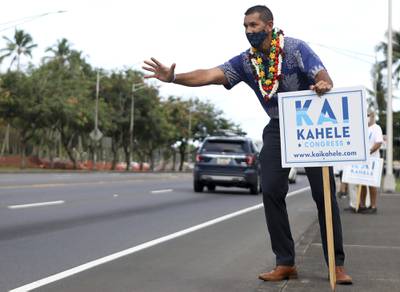 U.S. House of Representatives candidate Kai Kahele waves at people passing by while campaigning with supporters in Hilo, Hawaii, on Wednesday, Oct. 28, 2020.
