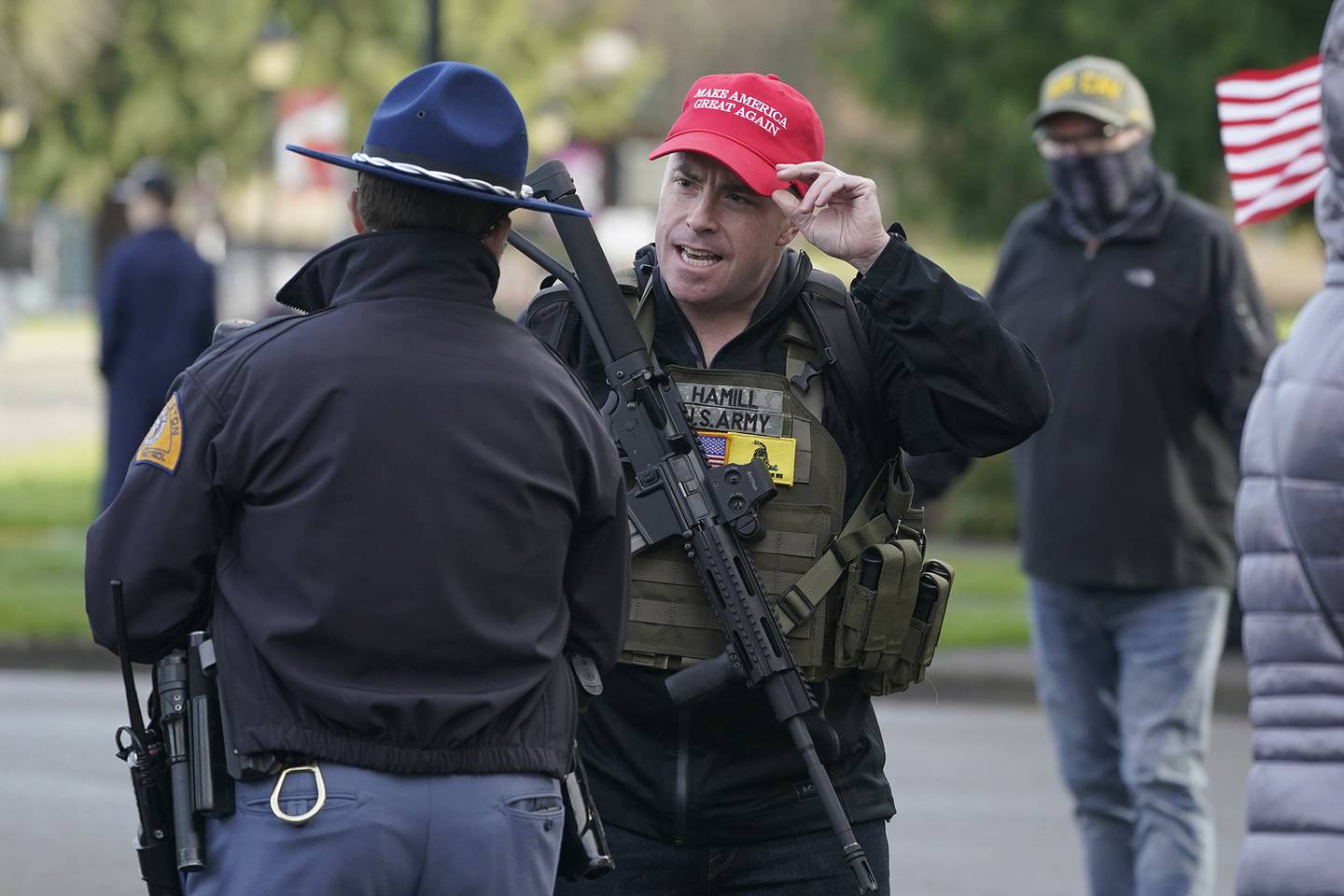 An armed supporter of President Donald Trump speaks casually with a Washington State Patrol trooper during a rally, Sunday, Jan. 10, 2021, at the Capitol in Olympia, Wash.