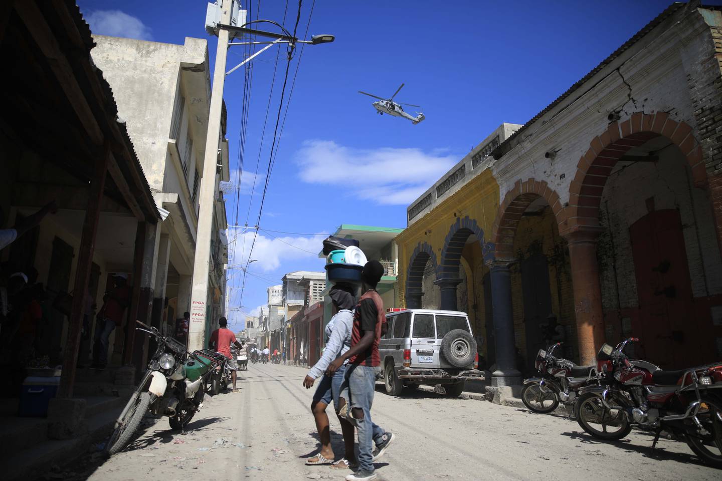 A USN helicopter flies overhead during a protest against the arrival of the USNS Comfort hospital ship in Jeremie, Haiti, Tuesday, Dec. 13, 2022.