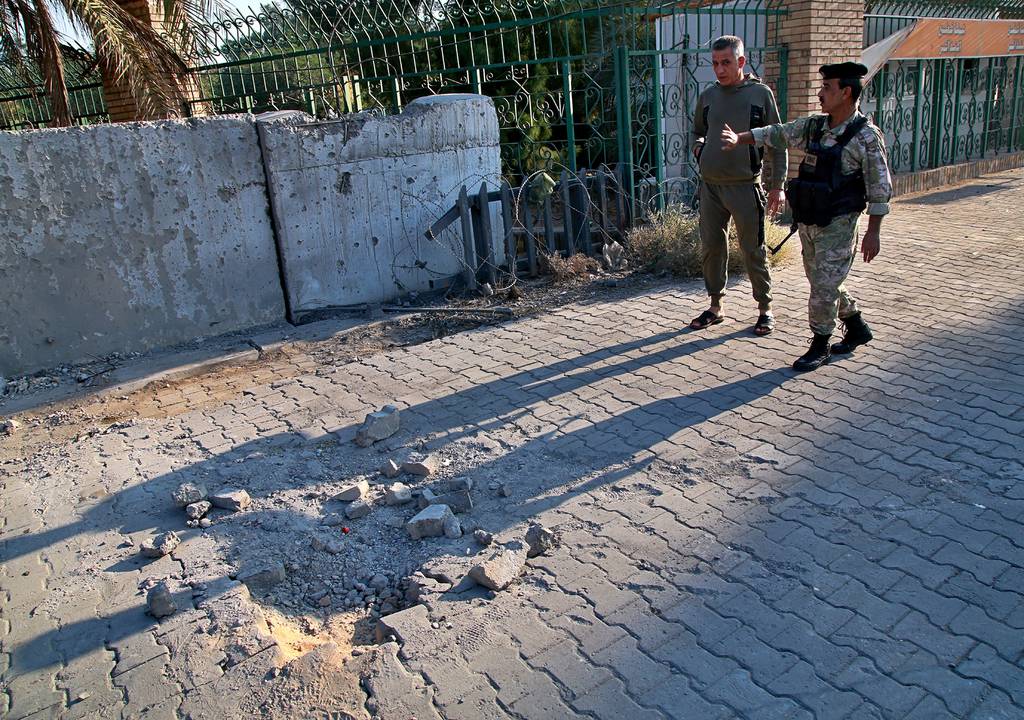 Security forces inspect the scene of the rocket attack at the gate of al-Zawra public park in Baghdad, Iraq, Nov. 18, 2020.