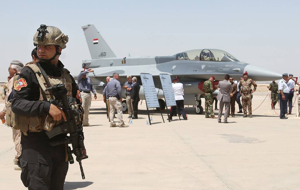 A member of the Iraqi SWAT team stands guard as security forces and others gather next to a U.S.- made F-16 fighter jet on July 20, 2015, during the delivery ceremony at Balad air base, Iraq.