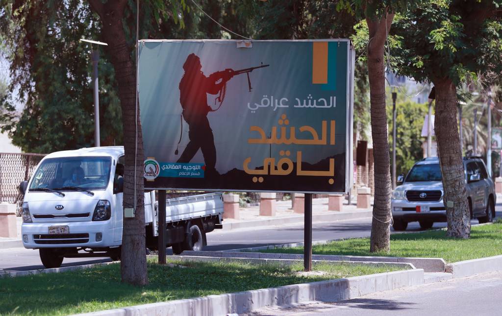 Motorists pass by a Popular Mobilization poster in Baghdad, Iraq, on June 26, 2020. Iraqi security forces arrested over a dozen men suspected of a spate of rocket attacks against the U.S.