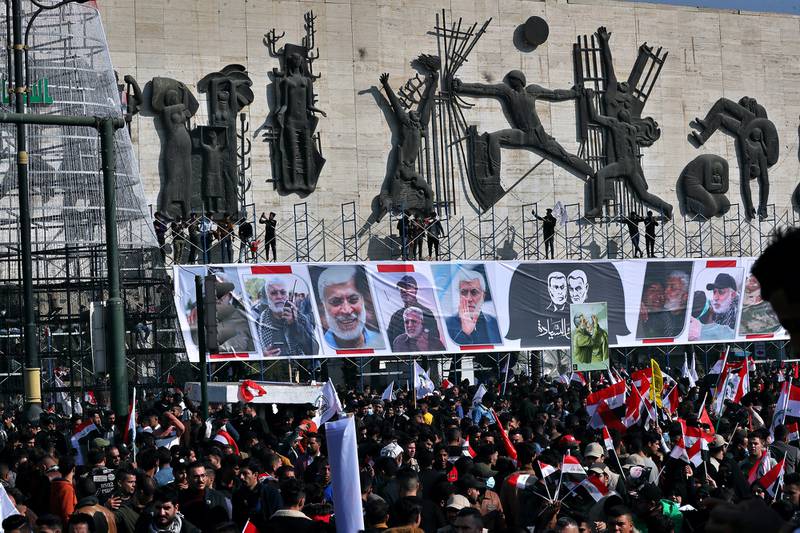 Supporters of the Popular Mobilization Forces hold a posters of Abu Mahdi al-Muhandis, deputy commander of the Popular Mobilization Forces, front, and Gen. Qassem Soleimani, head of Iran's Quds force during a protest, in Tahrir Square, Iraq, Sunday, Jan. 3, 2021.
