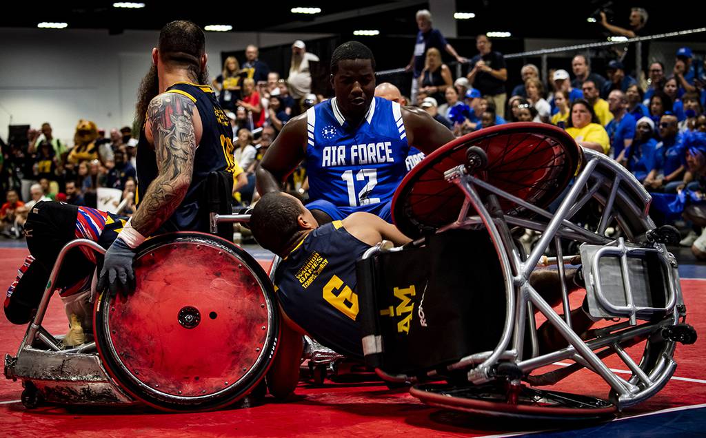 Air Force Senior Airman DeMarcus Garrett, Team Air Force athlete, powers through Team Navy defenders during the Department of Defense Warrior Games wheelchair rugby finals